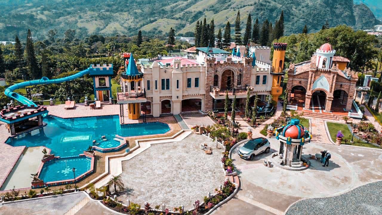 Aerial view of the castle venue with pools, water slide and mountain backdrop